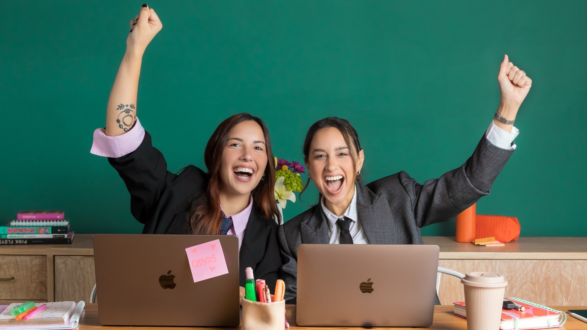 Maru y Mili celebrando frente a sus laptops